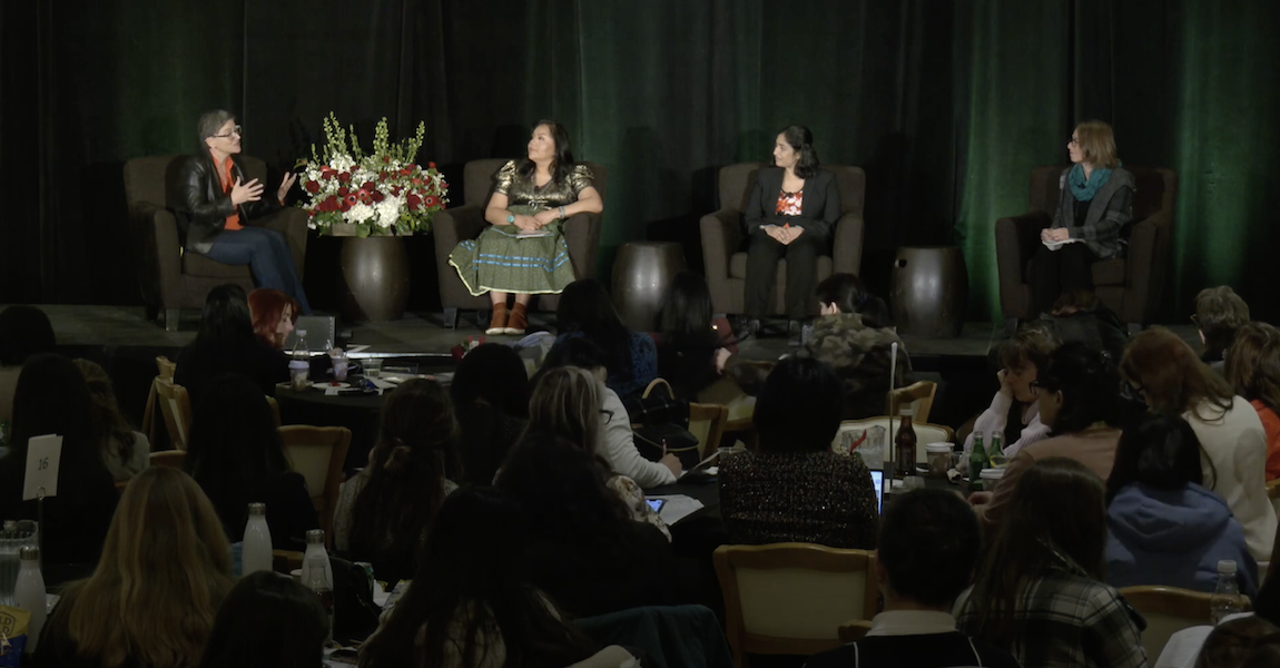 Four women sitting on stage during a conference panel.