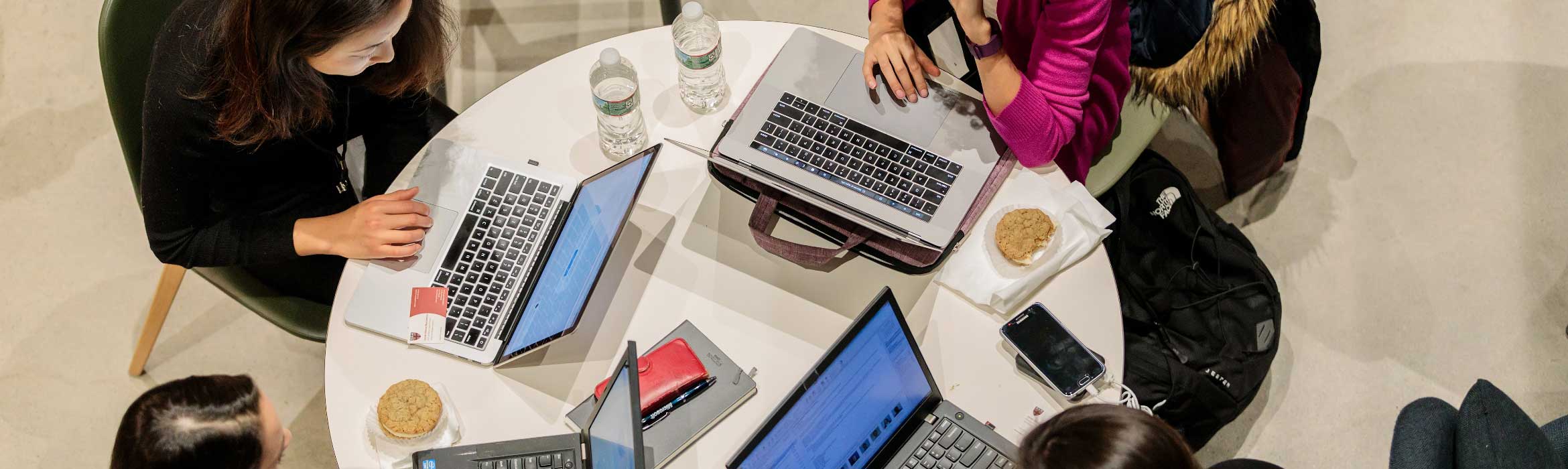 Group of women sitting on a round table with their laptops open