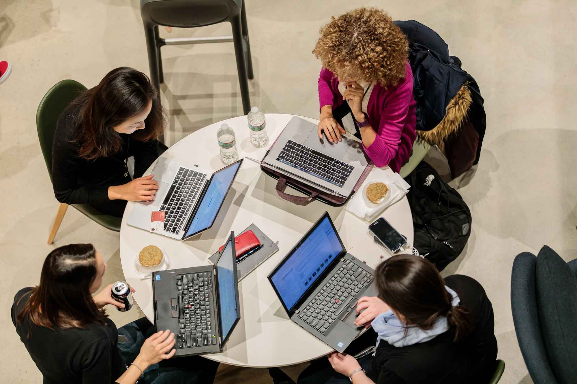 Group of women sitting on a round table with their laptops open